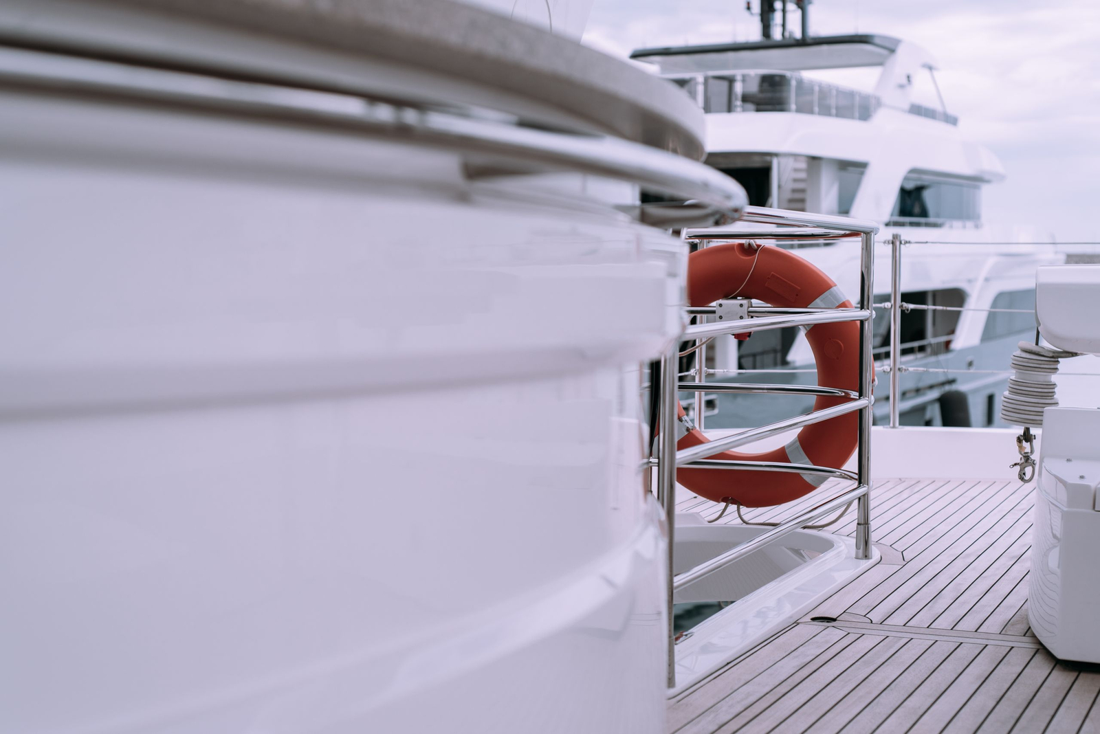 The deck of a large motor yacht in white and teak