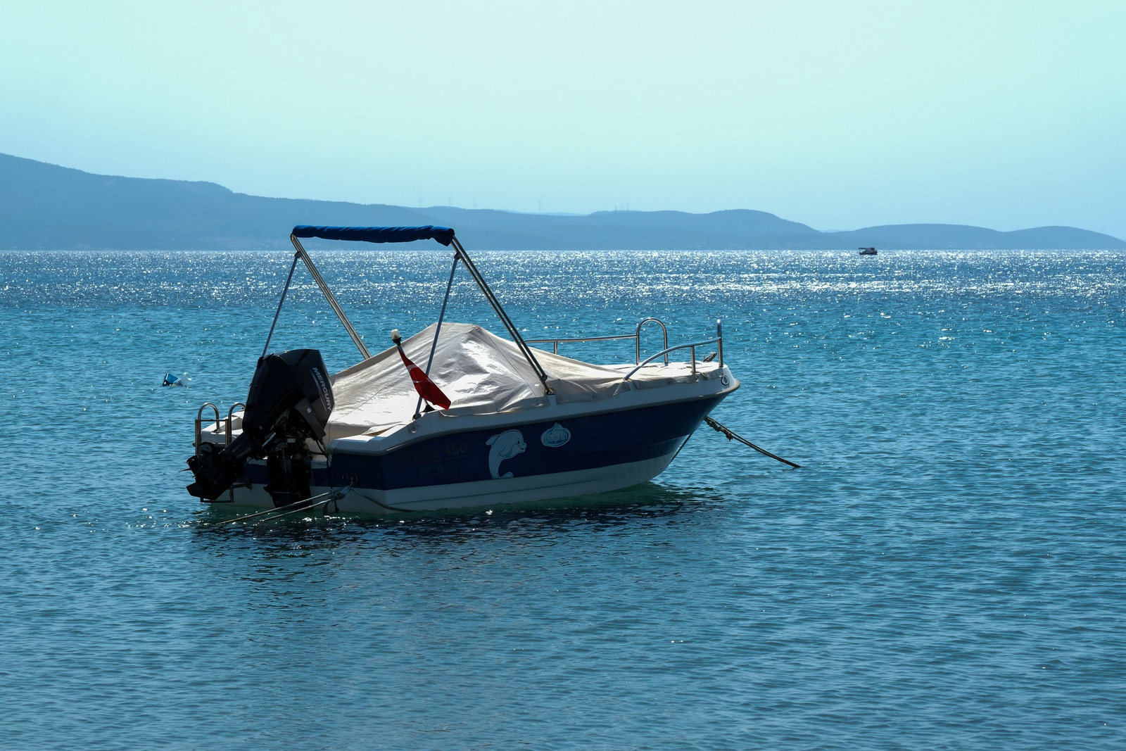 A small motorboat at anchor on calm blue water