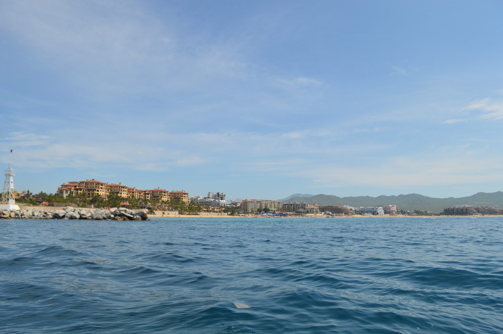 Cabo San Lucas seen from a boat, with the beach, the town and the desert mountains behind it